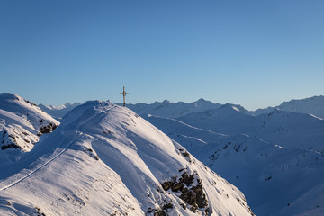 Gipfelkreuz unter blauem Himmel im Winter