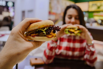 couple eat cheeseburgers in cafe