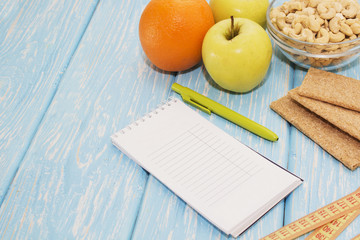 Healthy diet, fitness and weight loss concept, apple, notepad, pencil, measuring tape on the table. View from above.