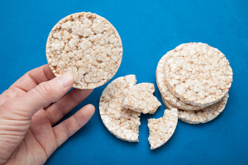 White puffed crispbread on hand isolated on blue.