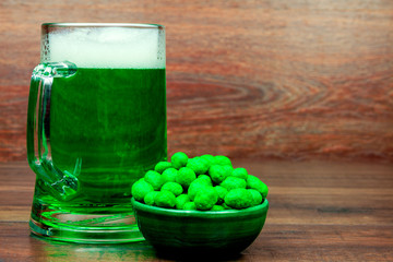 Saint Patrick's Day. Green glass pint of beer and green snacks cookies sweets on wooden background