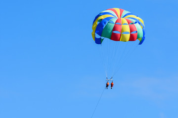 Fototapeta na wymiar Tourists enjoying island parasailing in a blue sky of Roatan, Honduras.