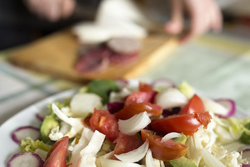 Salad in the foreground and the background a person working out of focus