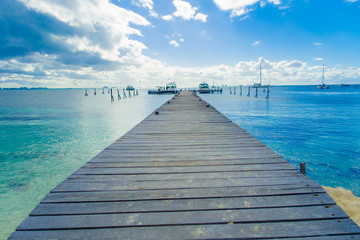 Outdoor view of a wooden dock into blue tropical sea in Isla Mujeres, Yucatan Mexico