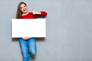 Smiling woman in red holding white sign board.