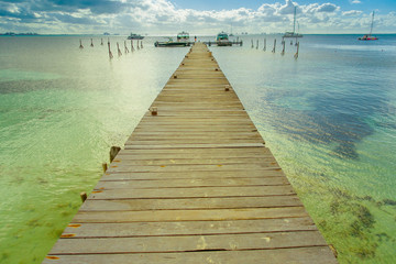 Beautiful outdoor view of a wooden dock into blue tropical sea in Isla Mujeres, Yucatan Mexico