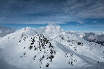 Berglandschaft im Winter unter blauem Himmel und Wolken