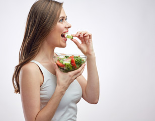 Happy young woman eating salad with cucumber.