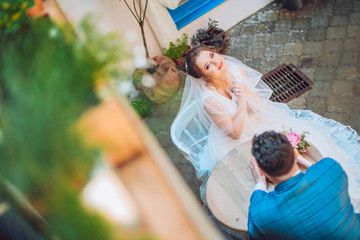 bride and groom sitting in a cozy cafe on the summer terrace. Newlyweds wedding day. Urban space resaurant.