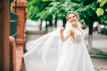 Naklejka premium Gorgeous bride looks up in the sky standing on summer street. Beautiful woman on her wedding day.