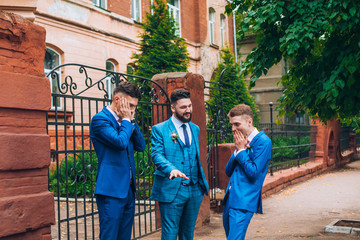 Groom and groomsmen look funny standing in the garden. Best friends on wedding day.