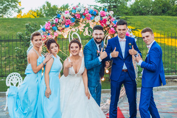 Fototapeta premium elegant stylish happy guests and bride and groom having funny photos on the background of arch, photo booth. Wedding moments with bridesmaids and groomsmen.