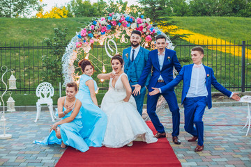 elegant stylish happy guests and bride and groom having funny photos on the background of arch,...