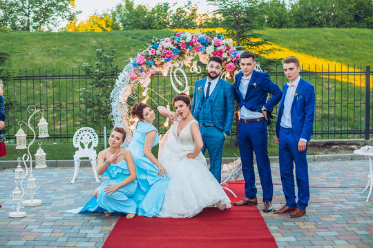 elegant stylish happy guests and bride and groom having funny photos on the background of arch, photo booth. Wedding moments with bridesmaids and groomsmen.