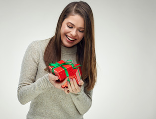 Smiling woman holding red gift with green ribbon and looking at