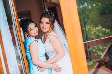 Portrait of bride with bridesmaid in hotel hall.