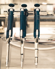 A set of various replicating pipettes in a research laboratory sitting on their stand ready for...