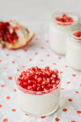 homemade yogurt with pomegranate seeds in jars on a napkin in polka dots