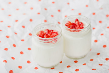 homemade yogurt with pomegranate seeds in jars on a napkin in polka dots