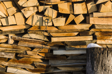 Holzstapel aus ordentlich aufgeschichteter Scheitholz und Kleinholz  zum trocknen für Kaminholz, Brennholz, Rohstoff, Holzmiete mit Schneeresten und Hackklotz