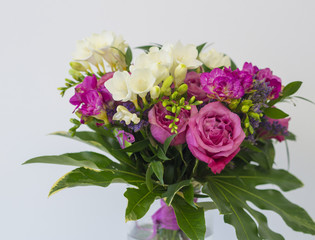 close up pink rose and white freesia flower bouquet with green leaves, decorative floral arangement on white background