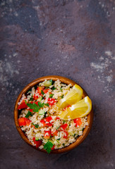 Tabbouleh salad with couscous on the plate.Traditional middle eastern or arab dish.Vegetarian.Parsley,pepper,cucumber,tomato,lemon.Middle eastern meze.Food or Healthy diet concept.Copy space for Text.
