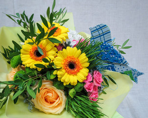 Obraz na płótnie Canvas Bright yellow bouquet. Beautiful gerberas and roses with grass and plants in a yellow kraft buimage - author's bouquet of a florist.