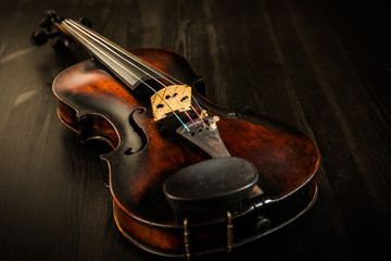 Old violin in vintage style on wood background