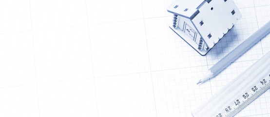 Wooden model of house, pencil and ruler on plotting paper