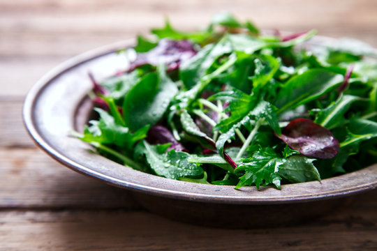 Fresh Green Mix Salad on Vintage Wooden background in a metal bowl.Leaves Of Spinach,Arugula,Romaine,Lettuce.Concept of Healthy Food.Vegetarian.Copy space for Text. selective focus.