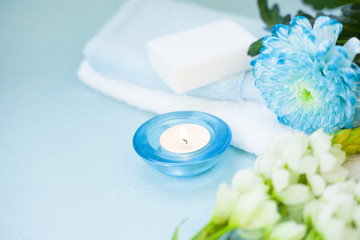 Aromatherapy spa concept with towel, candle, flowers on blue background, instagram
