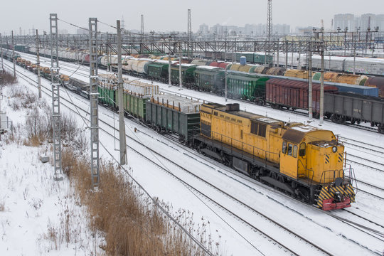 Freight Train To The Marshalling Yard In Winter In The Snow. Yellow Locomotive.