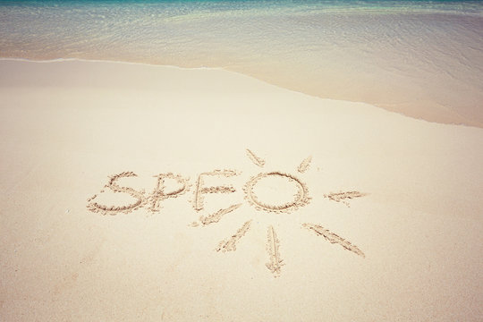 Written word SPF and drawing sun an sandy beach