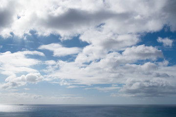 Naklejka na ściany i meble beautiful cloudscape against blue sunny sky above ocean