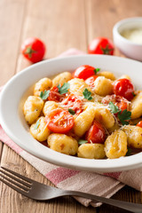 Homemade italian gnocchi with tomato, garlic, parsley and parmesan cheese on wooden table.