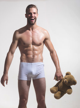 Happy man, handsome romantic macho with teddy bear. Nude young man with muscular torso, bearded macho holds teddy bear. Brutal caucasian hipster, attractive, sexy young male holds teddy bear in hands.