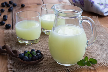 A jug of whey with blueberries in the background