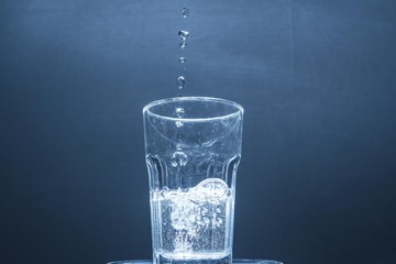 water drops falling into a half full glass of water, water photography, crystal clear water in a glass