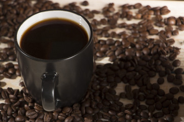 Seeds of coffee in a black cup on a wooden background