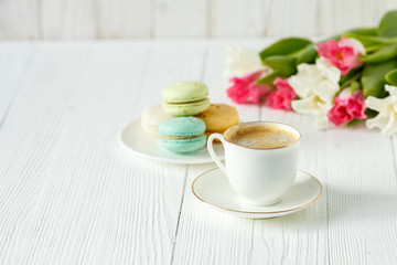 Fototapeta na wymiar Coffee, pink and white tulips and macarons on the white wooden table