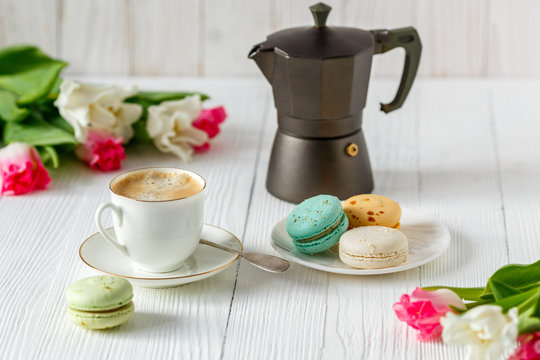 Coffee, pink and white tulips and macarons on the white wooden table