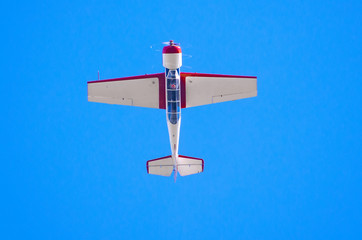 Airplane flys upside down in the blue sky.