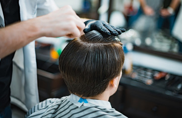 Man gets a cool haircut in barbershop. Barber makes the cut man electric razor. Men's care head. Soft focus.