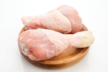 raw chicken legs on wooden base, isolated on white