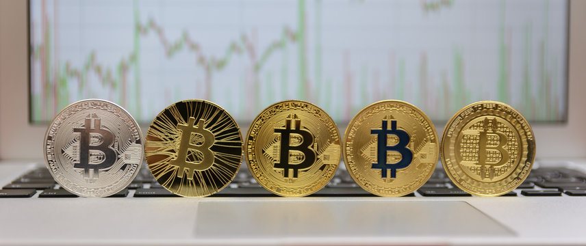  golden bitcoin on keyboard with chart on monitor
