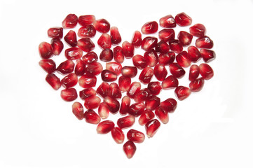 Bright red heart shape from pomegranate seeds isolated on white background,  raw juicy fruit