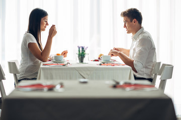 Obraz na płótnie Canvas Two casual young adults having a conversation over a meal.Formal proposal,talking in a restaurant.Trying food,offers,special menu.Happy couple eating course in hotel.Meeting,date,special occasion
