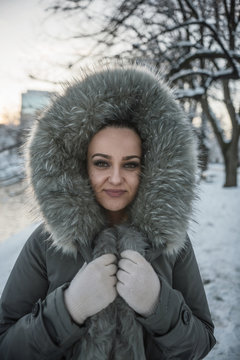 Portrait of a smiling woman standing in snow wearing a fake fur hood