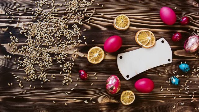 Easter red eggs,chicken and quail, lie on wooden table. Grain and slices dried orange, wooden tablet for text in center. Сolorful pastel easter eggs on wooden board background with space vintage toned