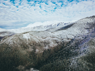 aerial drone shot of a winter snowy mountains above the clouds
